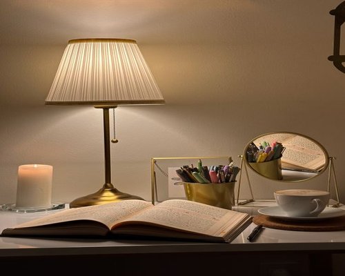 A cozy desk setup during a rainy day with a warm desk lamp casting local light downward onto an open book